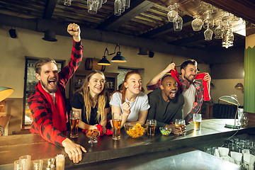 Image showing Sport fans cheering at bar, pub and drinking beer while championship, competition is going