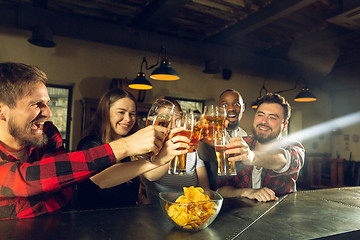 Image showing Sport fans cheering at bar, pub and drinking beer while championship, competition is going