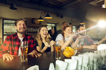 Image showing Sport fans cheering at bar, pub and drinking beer while championship, competition is going