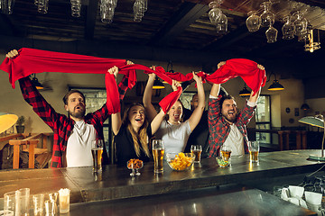 Image showing Sport fans cheering at bar, pub and drinking beer while championship, competition is going