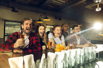 Image showing Sport fans cheering at bar, pub and drinking beer while championship, competition is going