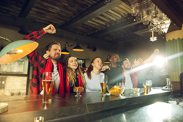 Image showing Sport fans cheering at bar, pub and drinking beer while championship, competition is going