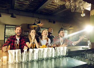 Image showing Sport fans cheering at bar, pub and drinking beer while championship, competition is going