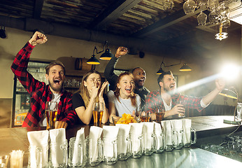 Image showing Sport fans cheering at bar, pub and drinking beer while championship, competition is going