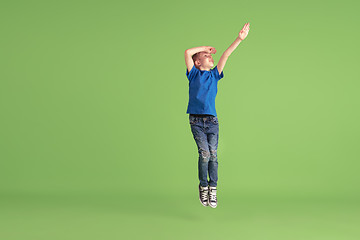 Image showing Happy boy playing and having fun on green studio background, emotions