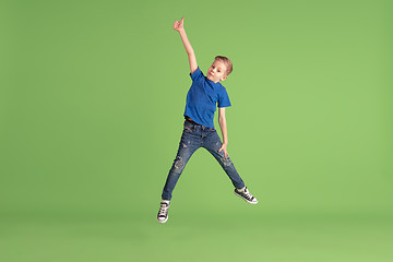 Image showing Happy boy playing and having fun on green studio background, emotions