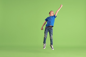 Image showing Happy boy playing and having fun on green studio background, emotions