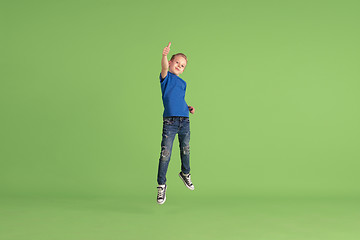 Image showing Happy boy playing and having fun on green studio background, emotions