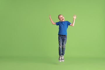 Image showing Happy boy playing and having fun on green studio background, emotions