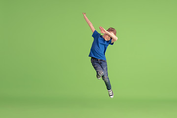 Image showing Happy boy playing and having fun on green studio background, emotions