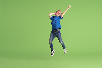 Image showing Happy boy playing and having fun on green studio background, emotions