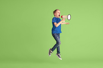 Image showing Happy boy playing and having fun on green studio background, emotions