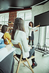 Image showing Female african-american speaker giving presentation in hall at university workshop