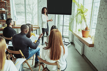 Image showing Female african-american speaker giving presentation in hall at university workshop