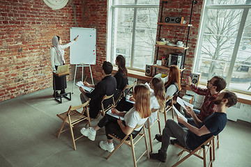 Image showing Female muslim speaker giving presentation in hall at university workshop