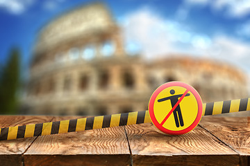 Image showing Warning sign with crossed out man on the background of wooden table and blurred Colosseum in Rome, Italy.