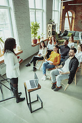 Image showing Female african-american speaker giving presentation in hall at university workshop