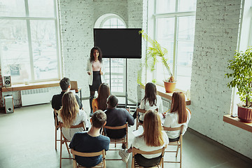 Image showing Female african-american speaker giving presentation in hall at university workshop