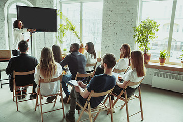 Image showing Female african-american speaker giving presentation in hall at university workshop