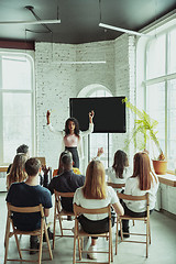 Image showing Female african-american speaker giving presentation in hall at university workshop