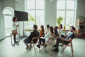 Image showing Female african-american speaker giving presentation in hall at university workshop