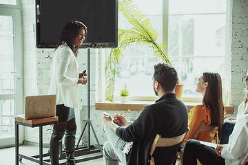 Image showing Female african-american speaker giving presentation in hall at university workshop