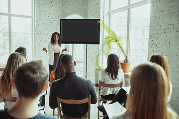 Image showing Female african-american speaker giving presentation in hall at university workshop