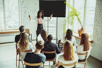 Image showing Female african-american speaker giving presentation in hall at university workshop