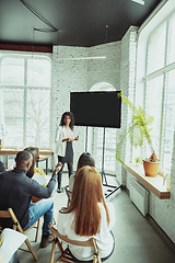 Image showing Female african-american speaker giving presentation in hall at university workshop