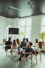 Image showing Female african-american speaker giving presentation in hall at university workshop