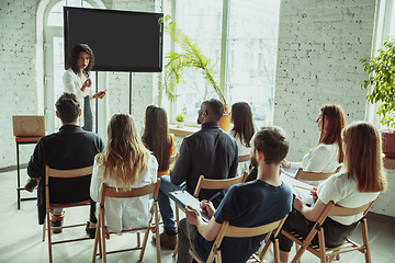 Image showing Female african-american speaker giving presentation in hall at university workshop