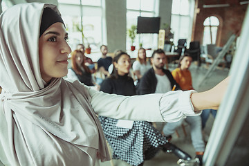 Image showing Female muslim speaker giving presentation in hall at university workshop