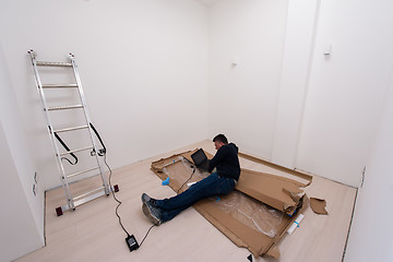 Image showing man using laptop while lying on cardboard box