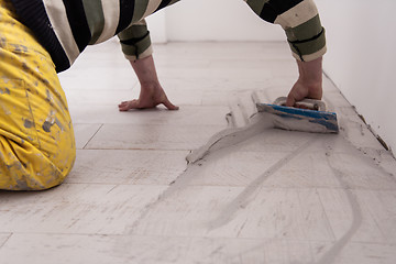 Image showing Tilers filling the space between ceramic wood effect tiles