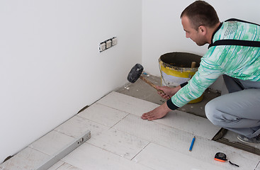 Image showing worker installing the ceramic wood effect tiles on the floor