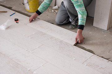 Image showing worker installing the ceramic wood effect tiles on the floor