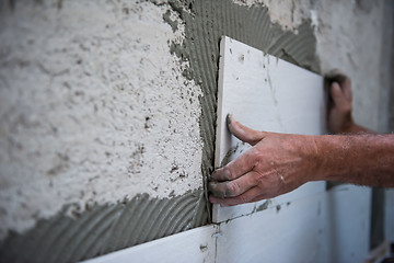 Image showing worker installing big ceramic tiles