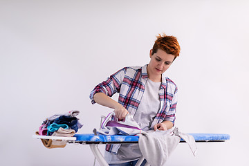 Image showing Red haired woman ironing clothes at home