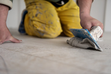 Image showing Tilers filling the space between ceramic wood effect tiles