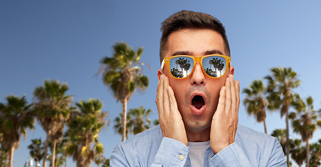 Image showing surprised man in sunglasses over palm trees