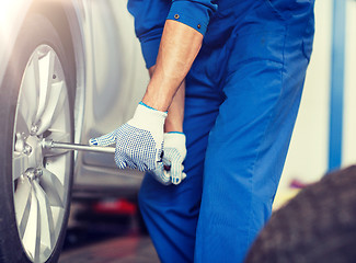 Image showing mechanic with screwdriver changing car tire