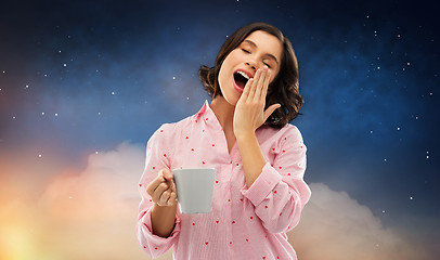 Image showing happy yawning young woman in pajama with coffee