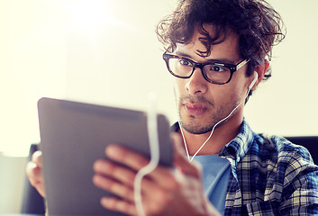 Image showing man with tablet pc and earphones sitting at cafe