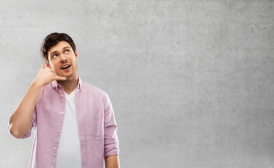 Image showing man showing phone call gesture over concrete wall