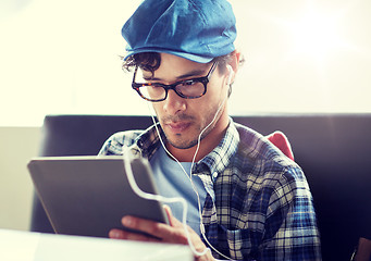 Image showing man with tablet pc and earphones sitting at cafe