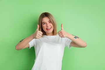 Image showing Caucasian young woman\'s portrait on green studio background