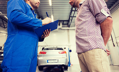 Image showing auto mechanic with clipboard and man at car shop