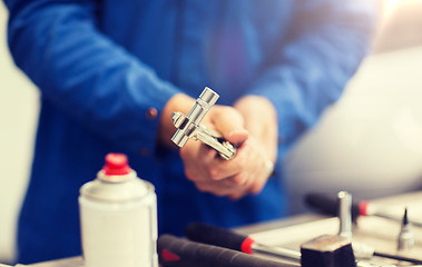 Image showing mechanic man with wrench repairing car at workshop