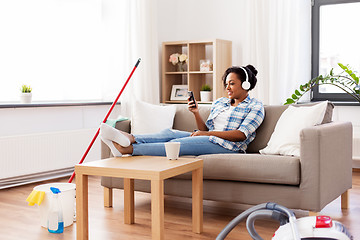 Image showing woman in headphones resting after home cleaning