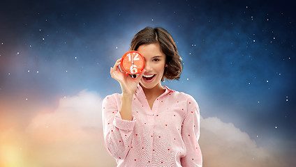 Image showing happy young woman in pajama with alarm clock